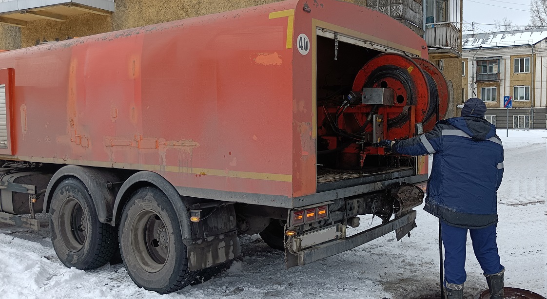 Каналопромывочная машина и работник прочищают засор в канализационной системе в Таштаголе