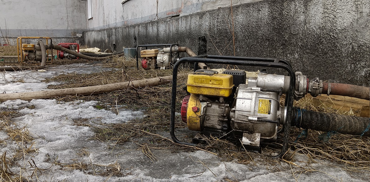 Откачка мотопомпами талой воды из подвала дома в Крапивинском